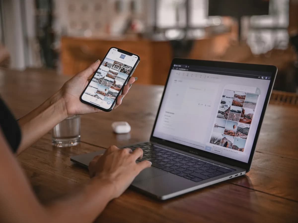 Ruka drží telefon se stejnou aplikací, jaká je otevřená na notebooku vedle